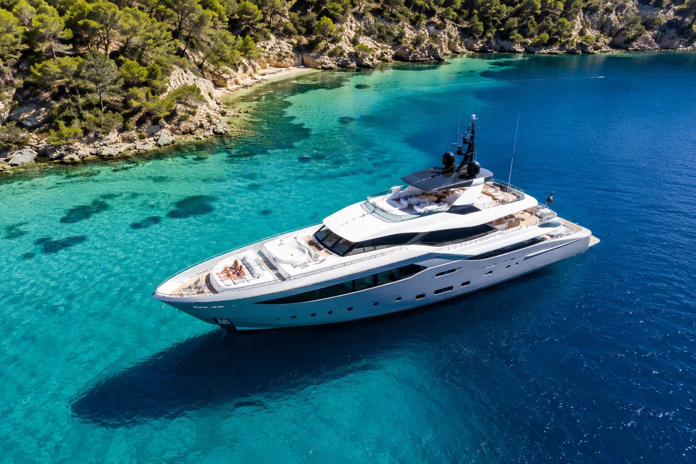 Majesty Charter — luxury superyacht anchored in a pristine bay seen from above with guests on the bow